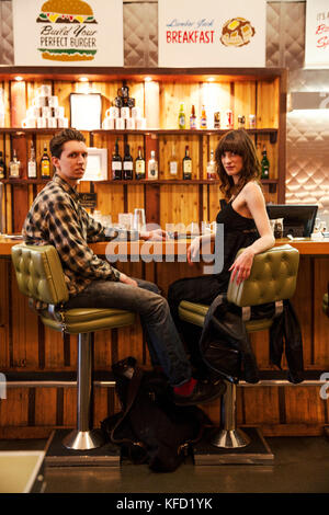 Canada, Vancouver (Colombie-Britannique), un couple local dîner au comptoir, enregistrer sur les viandes restaurant situé sur la rue Hastings ouest Banque D'Images