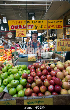 Canada, Vancouver, Colombie-Britannique, jeune homme vend des pommes à la Granville Island Public Market Banque D'Images