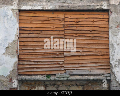 Texture bouclier en bois à l'intérieur d'un vieux mur de pierre, une fenêtre est obstruée par des planches de texture côtelée inhabituelle, un arrière-plan pour un intérieur moderne des Banque D'Images