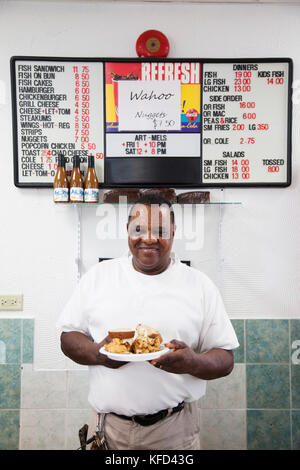 Les Bermudes. Saint George. Mel Art dans son restaurant appelé m'Art's Spicy Dicy. Il tient son fameux poisson Sandwich. Banque D'Images