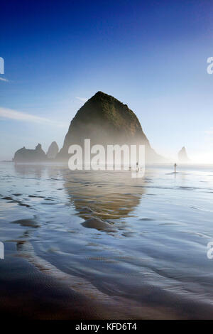 Usa (Oregon), Pacific City, les individus à pied le long de pacific city beach avec haystack rock dans la distance Banque D'Images