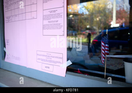 Petit drapeau américain est assis derrière une fenêtre d'un bureau de vote et un exemple bulletin est affiché sur l'extérieur, le jour du scrutin, à Philadelphie, PA Banque D'Images