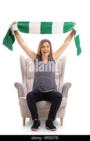 Heureux sports fan assise sur un fauteuil et acclamer avec un foulard isolé sur fond blanc Banque D'Images