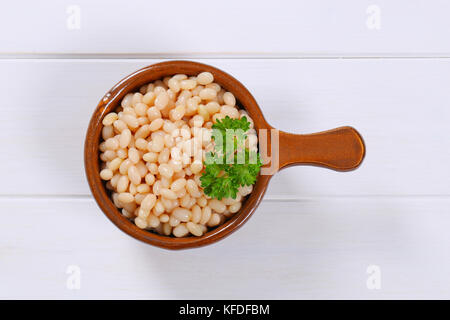 Casserole de haricots blancs en conserve sur fond de bois blanc Banque D'Images