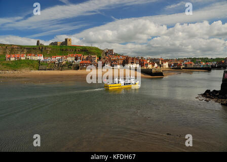 L'abbaye de Whitby et l'église St Mary sur la falaise est, vue de l'autre côté de l'entrée du port, quand un bateau touristique arrive. Banque D'Images