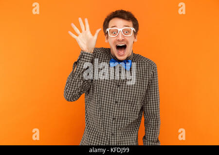 Bien bonjour ! L'homme fou des jeunes adultes et souriant à pleines dents montrant main à huis clos. studio shot. isolé sur fond orange Banque D'Images