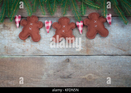 Guirlande de Noël faits à la main avec le gingembre et les hommes à des branches d'arbre de Noël sur le fond en bois rustique Banque D'Images