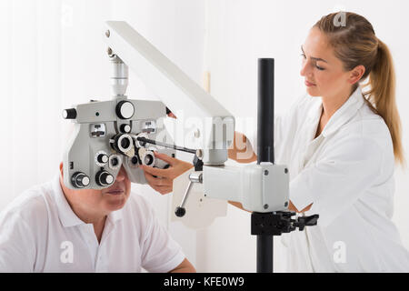 Happy female optométriste faire examen de la vue pour des patients en clinique Banque D'Images