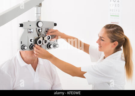 Happy female optométriste faire examen de la vue pour des patients en clinique Banque D'Images