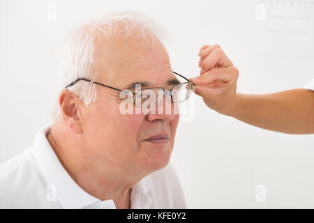 Close-up d'un opticien aider senior male patient avec de nouvelles lunettes Banque D'Images
