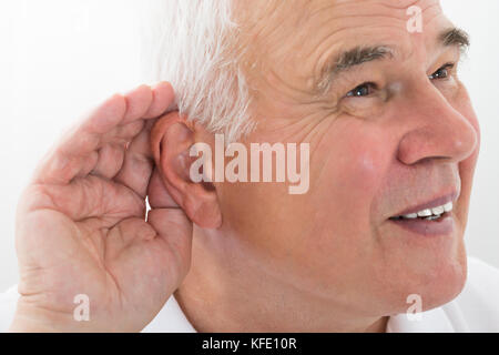 Man essaie d'écouter avec l'oreille de la main Banque D'Images