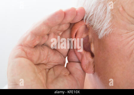 Close-up of a senior man essayant d'entendre d'oreille main Banque D'Images