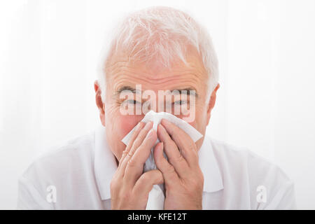 Close-up of senior homme infecté avec soufflage froid son nez en clinique Banque D'Images