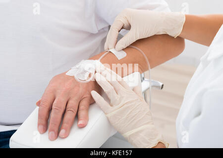 Close-up of main du médecin avec perfusion iv inséré dans la main du patient Banque D'Images