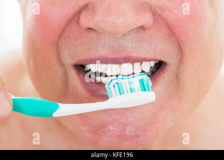 Portrait d'un homme se brosser les dents avec une brosse à dents Banque D'Images