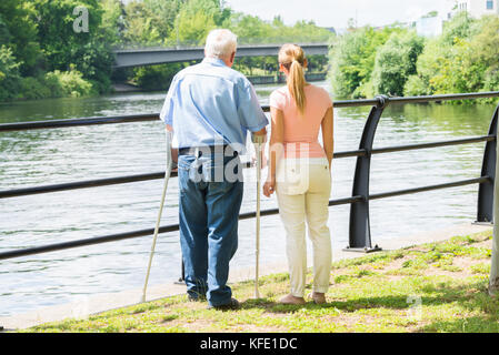 Vue arrière d'une jeune femme avec son père handicapé Banque D'Images