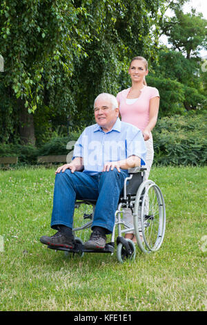 Jeune femme avec son père handicapé sur fauteuil roulant dans Park Banque D'Images