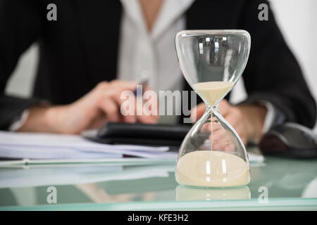 Close-up of businesswoman working in office avec hourglass sur 24 Banque D'Images