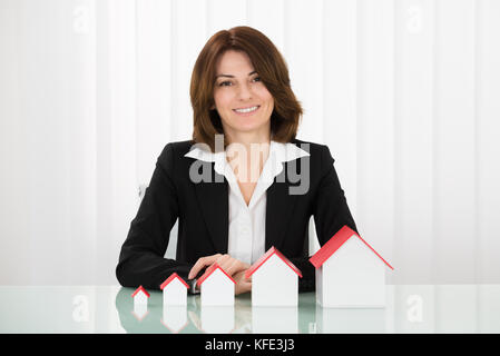 Happy young businesswoman showing plusieurs modèles de maison Banque D'Images