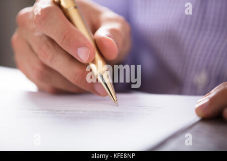 Close-up de la main de l'homme d'affaires signature document avec plume sur le bureau Banque D'Images