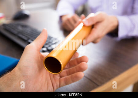 Close-up of a person's Hand passant à Baton de relais d'or Businessman Banque D'Images