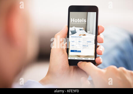 Close-up d'une personne titulaire d'un téléphone intelligent à l'aide de l'application en ligne Prix bas Hôtels Banque D'Images