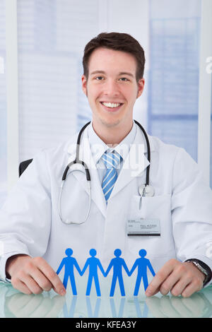 Portrait of young male doctor holding papier bleu, les gens à la chaîne 24 en clinique Banque D'Images