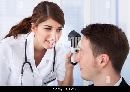 Young female doctor examining woman's front avec dermoscope en clinique Banque D'Images