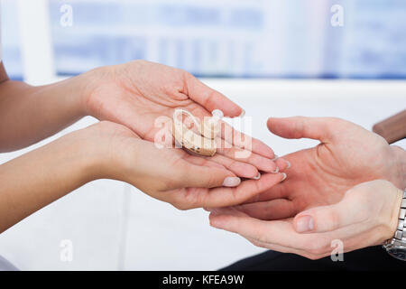 Portrait of female doctor giving appareil auditif pour male patient in clinic Banque D'Images