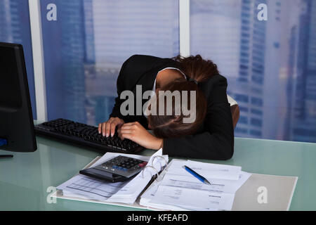 Surchargés de young businesswoman leaning at computer desk in office Banque D'Images
