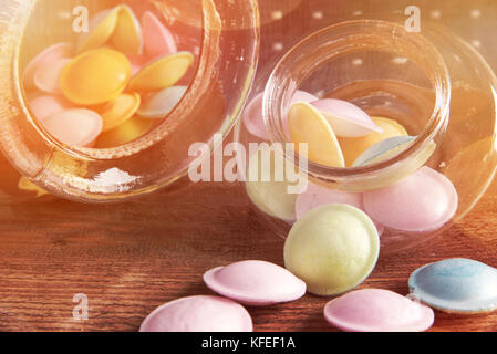 Bonbons colorés en pots sur le tableau sur fond de bois colorés de renverser de bonbons.un pot de rangement, sur fond sombre. Banque D'Images