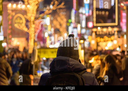 Un homme en face d'une rue du centre-ville de Séoul éclairée par les lumières de Noël Banque D'Images