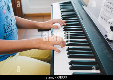 Petite fille de 9 ans à jouer du piano électrique en face de la partition du livre Banque D'Images