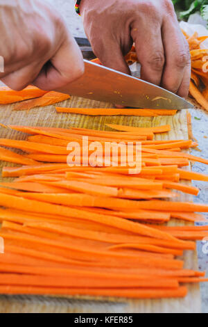 Man's hands, cut, julienne de carottes dans la cuisine Banque D'Images