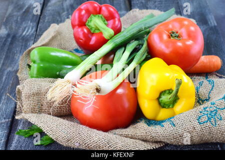 Légumes frais : paprika, tomate, oignon, carotte, sur un tissu textile rustique gris sur un fond de bois. la saine alimentation concept. Banque D'Images