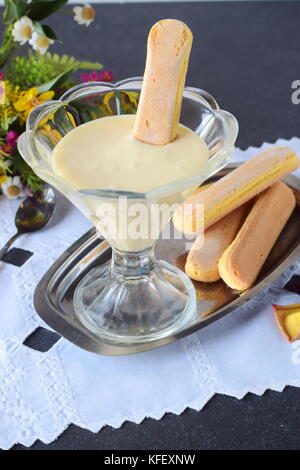 Pour la crème tiramisu dessert italien dans un bol en verre avec des biscuits Banque D'Images