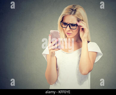 Femme en colère Ennuyé à lunettes à son téléphone intelligent avec frustration Banque D'Images