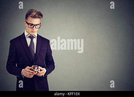 Closeup portrait of young man holding cube Rubik en lunettes Banque D'Images