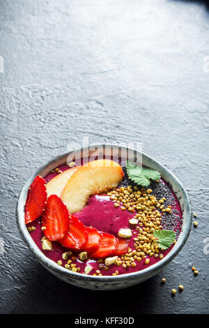 Smoothie acai bowl avec chia Graines, fruits, petits fruits (fraises) et du pollen d'abeille pour régime végétarien végétalien sain petit déjeuner smoothie déjeuner brutes. Banque D'Images