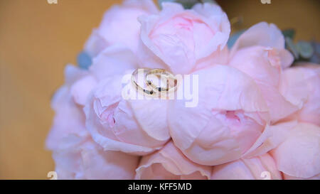 Anneaux de mariage sur un bouquet de fleurs blanches. anneaux de mariage et bouquet de fleur bleu foncé. Gros plan. Mariage Banque D'Images