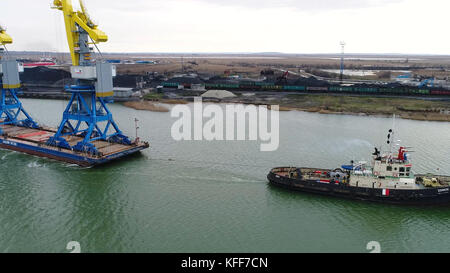 Grues de remorquage pour conteneurs. Grand porte-conteneurs tiré par des remorqueurs. Vue aérienne de haut en bas. Navire de fret de fret de conteneur avec pont de grue de travail dans le chantier naval au crépuscule pour le fond d'exportation d'importation logistique Banque D'Images