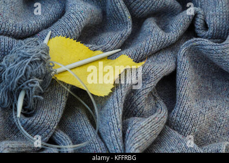 Arrière-plan de gris en tricot de laine de chèvre faites avec des aiguilles à tricoter ou sur une machine à tricoter mis en ondes avec des aiguilles à tricoter en métal, jaune Banque D'Images