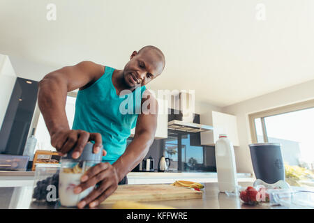 L'homme préparer milk shake en cuisine. L'homme d'ajouter les fruits et le lait dans un blender. Banque D'Images