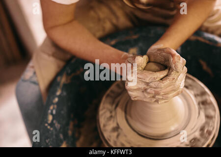 Potter faire un pot en argile sur les poteries roue en atelier. Artisane de la pâte à modeler avec les mains sur les poteries roue. Banque D'Images