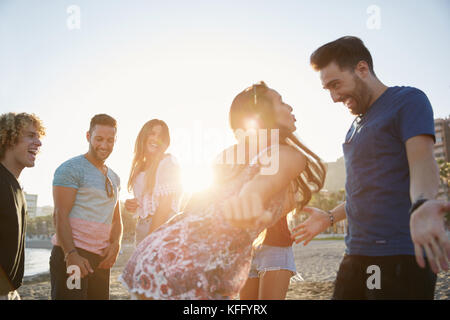 Portrait de couple dancing on beach à faire la fête avec des amis Banque D'Images