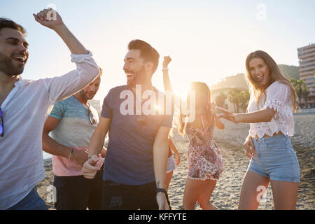 Portrait de jeunes femmes dansant avec leurs petits amis on beach Banque D'Images