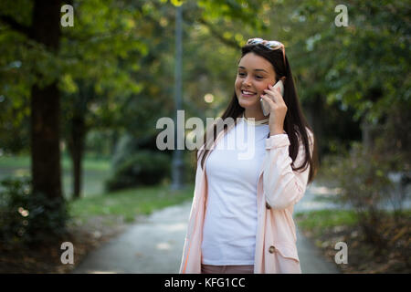 Jeune fille parler heureusement par téléphone intelligent Banque D'Images