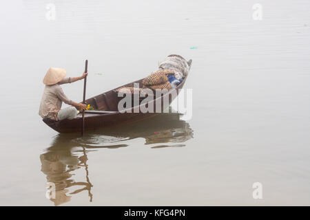 Une femme voile dans la brume sur la rivière Hoi An, Vietnam Banque D'Images