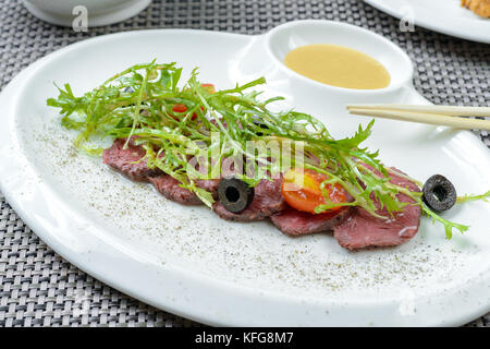 Boeuf grillé avec sauce et salade de pissenlit préparées Banque D'Images