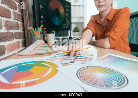 Gros plan du smiling woman holding bureau de design et d'un crayon de papier en couleur avec la palette de pointage selective focus photo. Banque D'Images